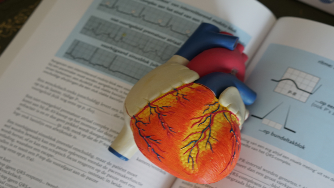 Artificial heart lying on a medical textbook