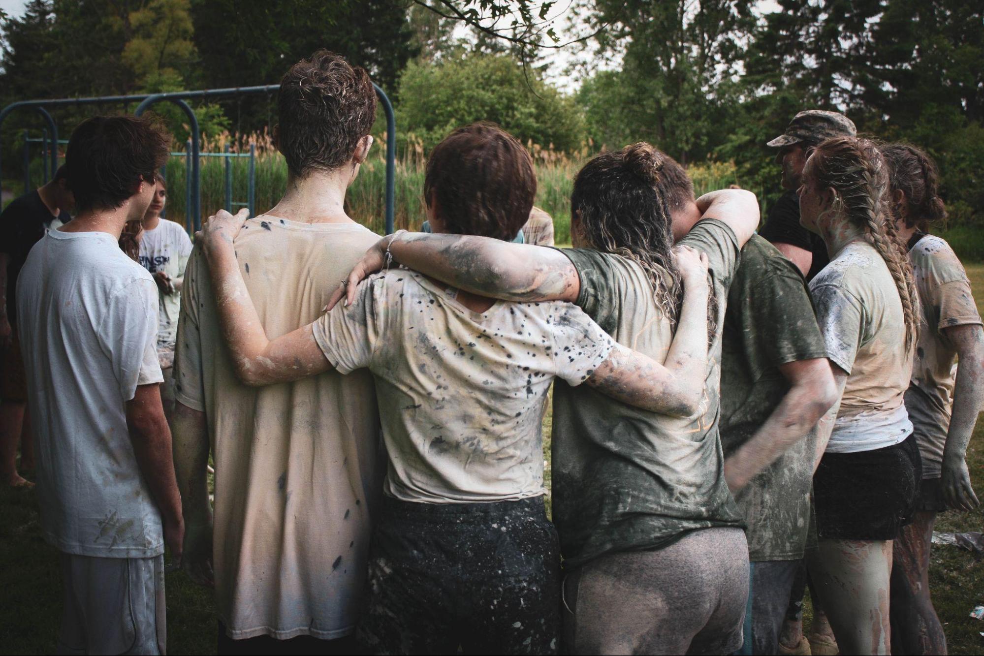 The back view of a group of teens standing with arms around each other